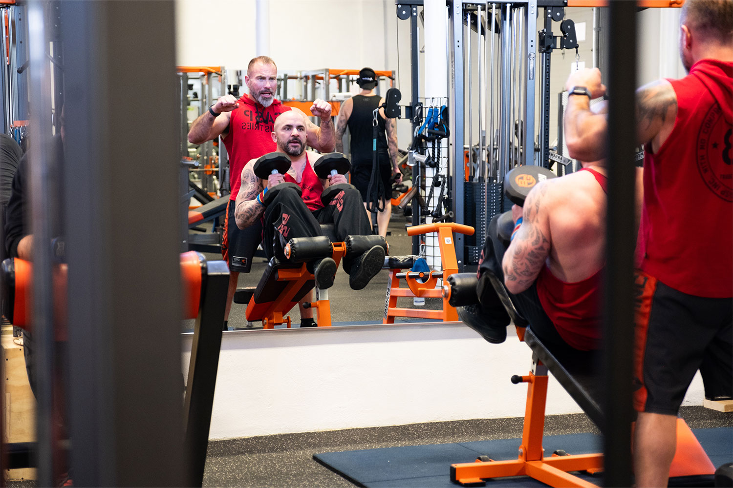 Trainer teaching a beginner how to set up a strength machine at Brickhouse Gym in Regina